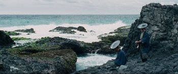 Movie still from “Silence” (2016), directed by Martin Scorsese – A person sitting on a rock near the ocean; Extreme Wide shot, High angle