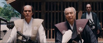 Movie still from “Silence” (2016), directed by Martin Scorsese – Two men in traditional garb sitting next to each other; Medium shot, Low angle