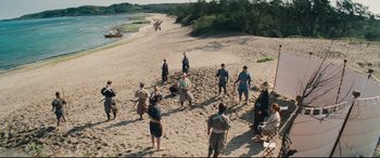 Movie still from “Silence” (2016), directed by Martin Scorsese – A group of people standing on top of a sandy beach; Extreme Wide shot, High angle