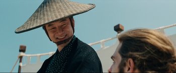 Movie still from “Silence” (2016), directed by Martin Scorsese – A man wearing a straw hat and smiling for the camera; Close Up shot, Over the shoulder angle