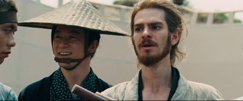 Movie still from “Silence” (2016), directed by Martin Scorsese – A man with long hair and a hat is holding a baseball bat; Close Up shot, Low angle