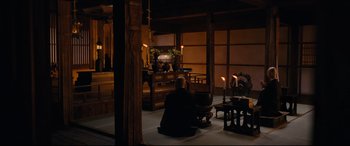 Movie still from “Silence” (2016), directed by Martin Scorsese – A man sitting on the ground in a room with candles; Wide shot, High angle
