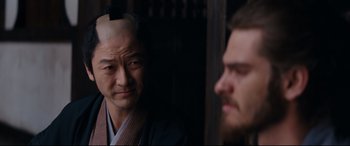 Movie still from “Silence” (2016), directed by Martin Scorsese – A man wearing a wig and a kimono looks at another man in a beard; Close Up shot, Over the shoulder angle