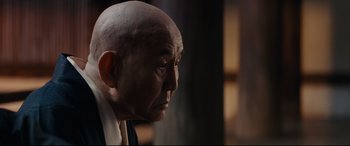 Movie still from “Silence” (2016), directed by Martin Scorsese – A bald man is looking off into the distance; Close Up shot, Over the shoulder angle