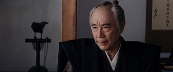 Movie still from “Silence” (2016), directed by Martin Scorsese – An older man wearing a black robe and a black hat; Close Up shot, Over the shoulder angle