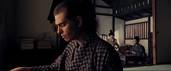 Movie still from “Silence” (2016), directed by Martin Scorsese – A young man in a kimono looking down at his face; Medium shot, Low angle