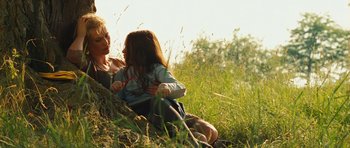 Movie still from “Silent Hill” (2006), directed by Christophe Gans – A woman and a child sitting in a field; Medium shot, Low angle
