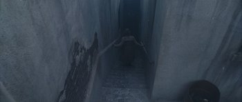 Movie still from “Silent Hill” (2006), directed by Christophe Gans – A woman walking down a set of stairs in the dark; Wide shot, Overhead angle