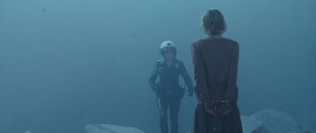 Movie still from “Silent Hill” (2006), directed by Christophe Gans – A woman in a white helmet is standing next to another woman in a blue dress; Wide shot, Over the shoulder angle