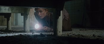 Movie still from “Silent Hill” (2006), directed by Christophe Gans – A woman laying on the ground holding a flashlight; Medium shot, Overhead angle