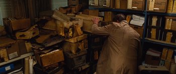 Movie still from “Silent Hill” (2006), directed by Christophe Gans – A man in a coat is reaching for boxes; Medium shot, High angle