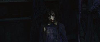 Movie still from “Silent Hill” (2006), directed by Christophe Gans – A young girl in a dark room wearing a blue shirt; Medium shot, High angle