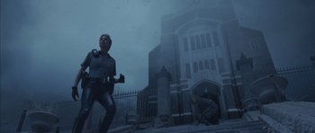 Movie still from “Silent Hill” (2006), directed by Christophe Gans – A man in a police uniform is running in front of a building; Wide shot, Low angle