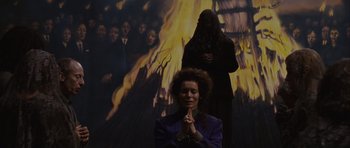 Movie still from “Silent Hill” (2006), directed by Christophe Gans – A woman praying in front of an image of a person in a black robe; Wide shot, Low angle