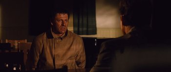 Movie still from “Silent Hill” (2006), directed by Christophe Gans – A man in a brown jacket sitting in front of another man in a brown jacket; Medium shot, Over the shoulder angle