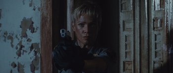 Movie still from “Silent Hill” (2006), directed by Christophe Gans – A woman holding a gun while standing next to a door; Close Up shot, Low angle