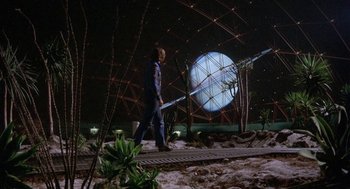 Movie still from “Silent Running” (1972), directed by Douglas Trumbull – A man is walking on a track in front of a building; Wide shot, Low angle