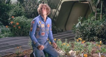 Movie still from “Silent Running” (1972), directed by Douglas Trumbull – A man in a blue suit kneeling in a flower garden; Medium shot, Low angle