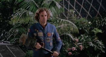 Movie still from “Silent Running” (1972), directed by Douglas Trumbull – A man holding an axe while standing next to trees; Medium shot, Low angle