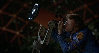 Movie still from “Silent Running” (1972), directed by Douglas Trumbull – A man holding a telescope up to his face; Medium shot, Low angle