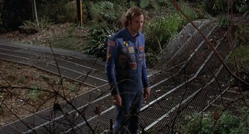 Movie still from “Silent Running” (1972), directed by Douglas Trumbull – A man in a blue suit standing next to a metal fence; Medium shot, Low angle