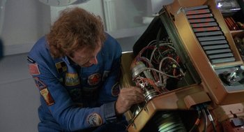 Movie still from “Silent Running” (1972), directed by Douglas Trumbull – A man working on an electrical device in a room; Medium shot, Overhead angle