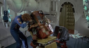 Movie still from “Silent Running” (1972), directed by Douglas Trumbull – A man standing in front of a chair with a computer on top of it; Medium shot, Overhead angle