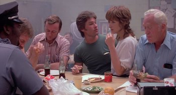 Movie still from “Silkwood” (1983), directed by Mike Nichols – A group of people sitting around a table eating; Medium shot, Over the shoulder angle