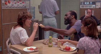 Movie still from “Silkwood” (1983), directed by Mike Nichols – A group of people sitting at a table eating food; Medium shot, Over the shoulder angle