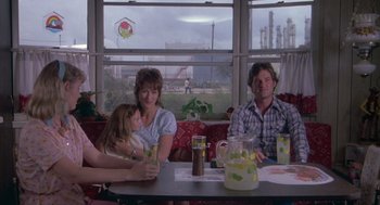 Movie still from “Silkwood” (1983), directed by Mike Nichols – A group of people sitting at a table with drinks; Medium shot, Over the shoulder angle