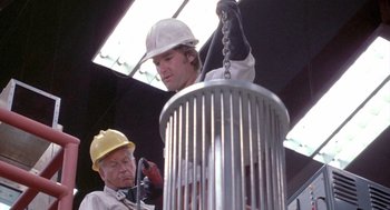 Movie still from “Silkwood” (1983), directed by Mike Nichols – Two men in hard hats working on an object in a factory; Medium shot, Low angle