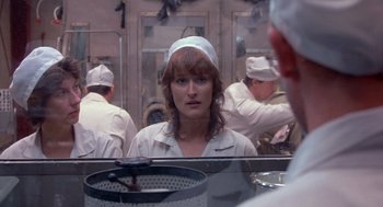 A woman is looking into a mirror in a kitchen