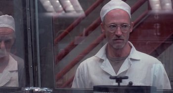 Movie still from “Silkwood” (1983), directed by Mike Nichols – A man in a white hat and glasses looking out of a window; Close Up shot, Low angle