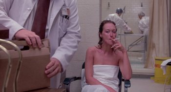 Movie still from “Silkwood” (1983), directed by Mike Nichols – A woman sitting in a chair smoking a cigarette; Medium shot, Low angle