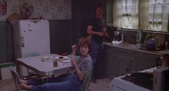 Movie still from “Silkwood” (1983), directed by Mike Nichols – A woman sitting at a table in front of a man in a kitchen; Wide shot, High angle