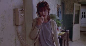 Movie still from “Silkwood” (1983), directed by Mike Nichols – A woman talking on a phone while standing next to a wall; Medium shot, Over the shoulder angle