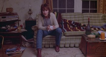 Movie still from “Silkwood” (1983), directed by Mike Nichols – A woman sitting on a couch holding a nintendo wii game controller; Medium shot, High angle
