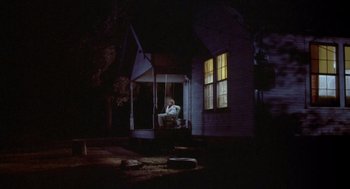 Movie still from “Silkwood” (1983), directed by Mike Nichols – A person sitting on a porch swing at night; Extreme Wide shot, Low angle