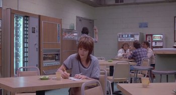 Movie still from “Silkwood” (1983), directed by Mike Nichols – A woman sitting at a table writing on a piece of paper; Wide shot, Over the shoulder angle