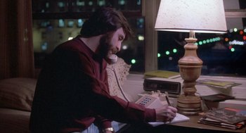 Movie still from “Silkwood” (1983), directed by Mike Nichols – A man sitting at a desk with a phone and a lamp; Medium shot, High angle