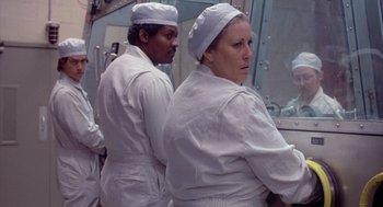 Movie still from “Silkwood” (1983), directed by Mike Nichols – A man and a woman in white lab coats and white hats; Medium shot, Over the shoulder angle