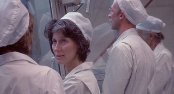 Movie still from “Silkwood” (1983), directed by Mike Nichols – A woman wearing a white hat in front of two men; Close Up shot, Over the shoulder angle