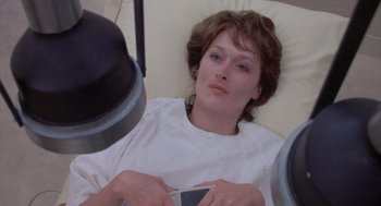 Movie still from “Silkwood” (1983), directed by Mike Nichols – A woman laying in a hospital bed holding a cell phone; Close Up shot, Overhead angle