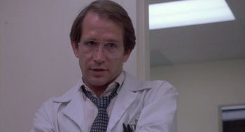 Movie still from “Silkwood” (1983), directed by Mike Nichols – A man in a white lab coat and a tie; Close Up shot, Low angle