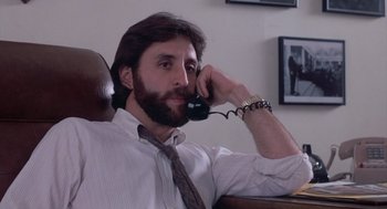 Movie still from “Silkwood” (1983), directed by Mike Nichols – A man sitting in a chair talking on a phone; Close Up shot, Low angle