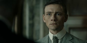 Movie still from “A Fortunate Man” (2018), directed by Bille August – A person wearing a suit and tie; Close Up shot, Low angle