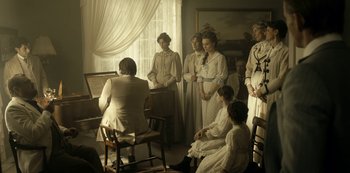 Movie still from “A Fortunate Man” (2018), directed by Bille August – A group of women standing in a living room; Wide shot, High angle