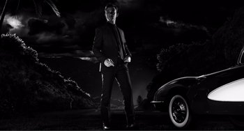 Movie still from “Sin City: A Dame to Kill For” (2014), directed by Frank Miller – A man standing next to a car in the dark; Wide shot, Low angle