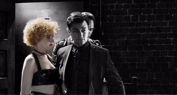 Movie still from “Sin City: A Dame to Kill For” (2014), directed by Frank Miller – A man and a woman standing next to each other in front of a brick wall; Medium shot, Low angle