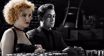 Movie still from “Sin City: A Dame to Kill For” (2014), directed by Frank Miller – A man and a woman sitting at a table in a room; Medium shot, Low angle